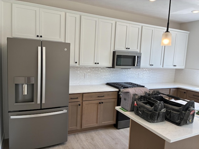 1973 Lowe Dr, Spring Lake, MI 49456 - kitchen featuring stainless steel appliances, light wood-type flooring, tasteful backsplash, hanging light fixtures, and light stone counters