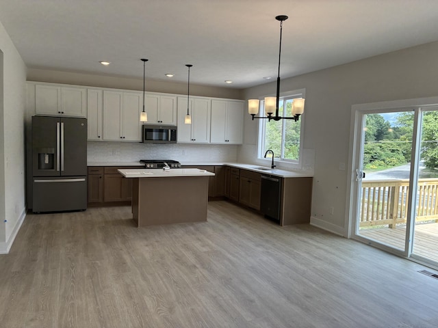 1973 Lowe Dr, Spring Lake, MI 49456 - kitchen with stainless steel appliances, light wood finished floors, light countertops, a center island, and decorative backsplash