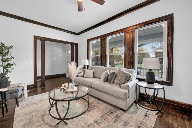 living area with a ceiling fan, baseboards, ornamental molding, and wood finished floors