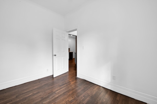 spare room featuring dark wood finished floors and baseboards