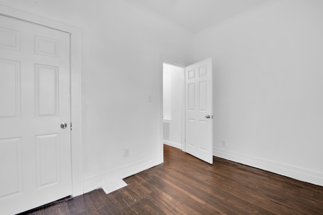 unfurnished bedroom with visible vents, baseboards, and dark wood finished floors