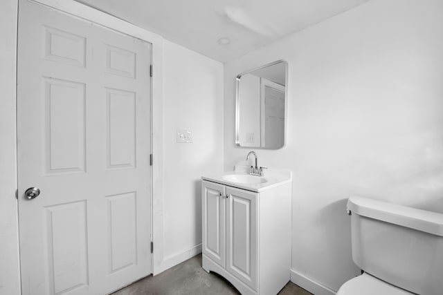 half bathroom with concrete flooring, vanity, toilet, and baseboards