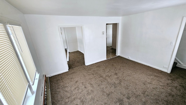 unfurnished bedroom featuring dark carpet and baseboards