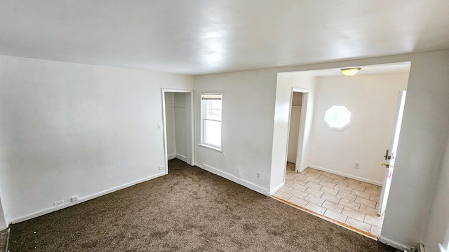 carpeted empty room featuring tile patterned flooring and baseboards