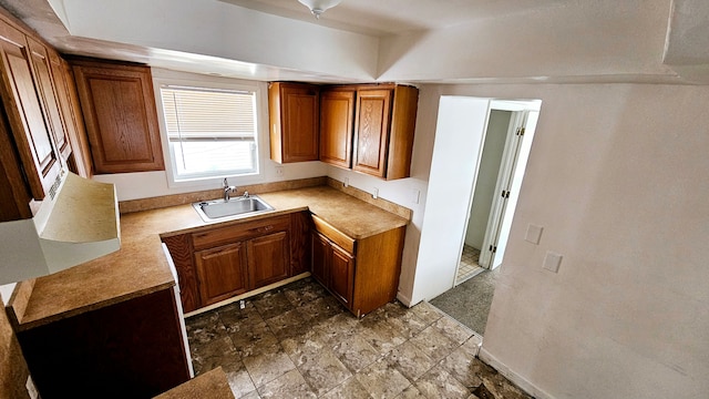 kitchen with light countertops, a sink, and brown cabinets