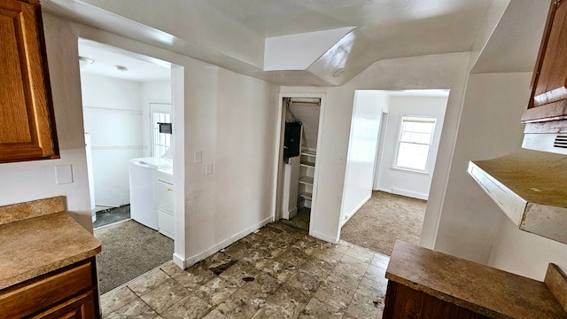 interior space with baseboards, carpet, independent washer and dryer, and brown cabinets