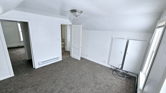 additional living space featuring baseboards, vaulted ceiling, a baseboard heating unit, and dark colored carpet