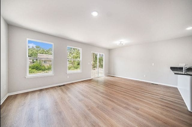 unfurnished living room featuring light wood finished floors, recessed lighting, visible vents, and baseboards