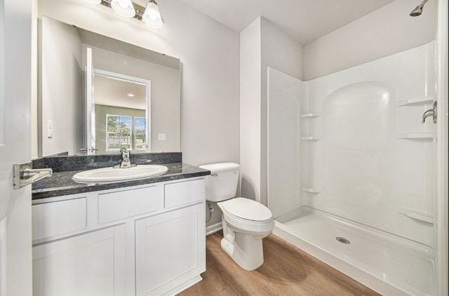 full bathroom featuring toilet, a stall shower, wood finished floors, and vanity