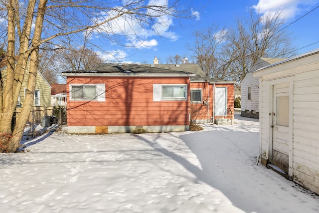 snow covered rear of property featuring fence