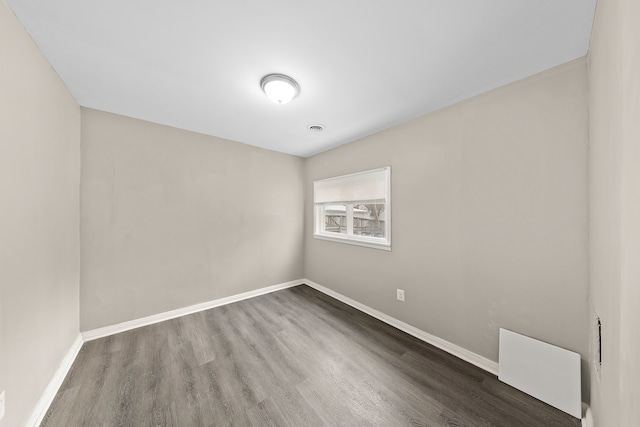 unfurnished room featuring wood finished floors, visible vents, and baseboards