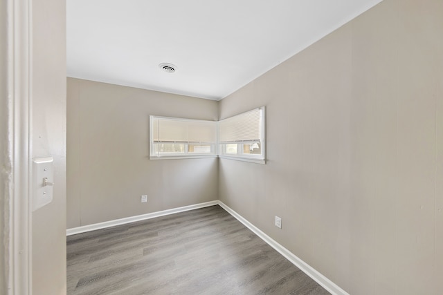 empty room featuring wood finished floors, visible vents, and baseboards