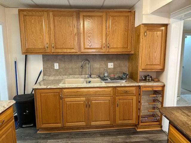 kitchen with tasteful backsplash, a sink, dark wood finished floors, and brown cabinets