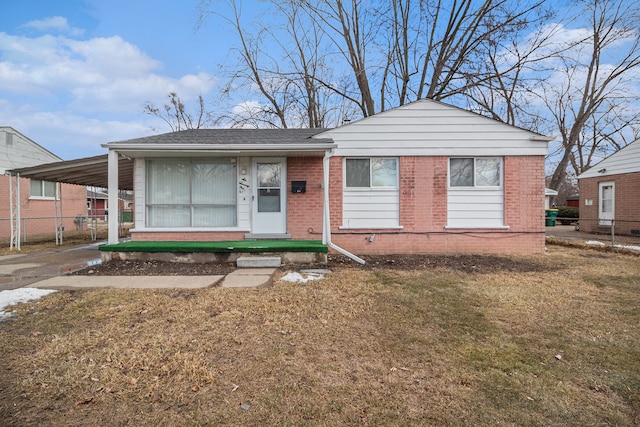 view of front of house with an attached carport, brick siding, fence, and a front lawn