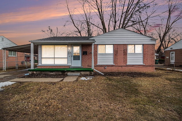 view of front of home with a front yard, brick siding, and an attached carport