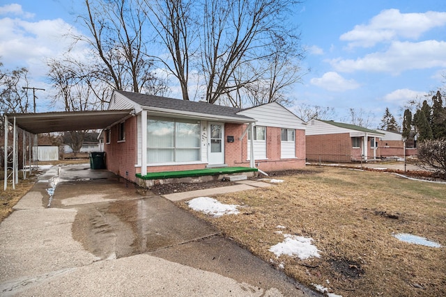 view of front facade with a front yard, an attached carport, concrete driveway, and brick siding