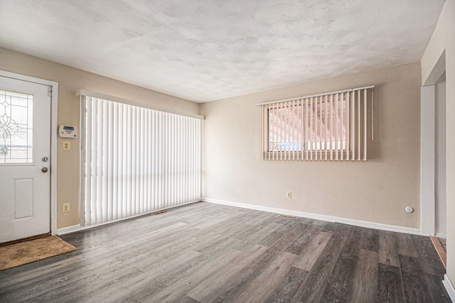 entrance foyer featuring visible vents, a textured ceiling, baseboards, and wood finished floors