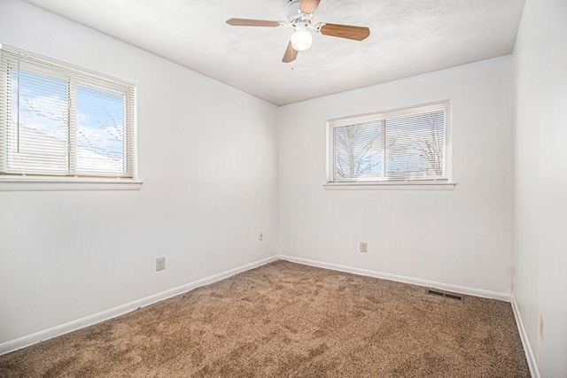 unfurnished room with carpet, a healthy amount of sunlight, visible vents, and baseboards