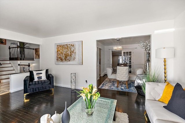 living area with dark wood-type flooring, baseboards, and stairs