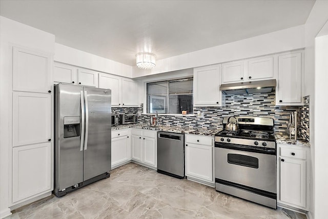 kitchen featuring tasteful backsplash, white cabinets, dark stone counters, stainless steel appliances, and under cabinet range hood