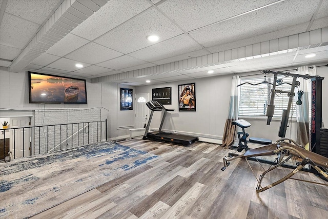 workout area featuring a paneled ceiling, recessed lighting, baseboards, and wood finished floors