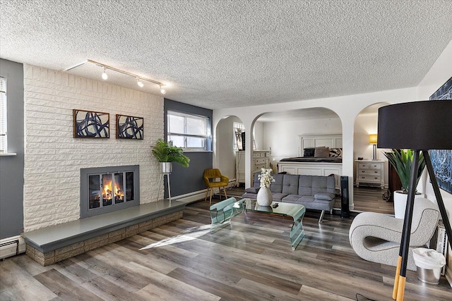 living room with a textured ceiling, arched walkways, a fireplace, and wood finished floors