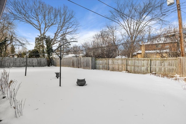 snowy yard featuring a fenced backyard