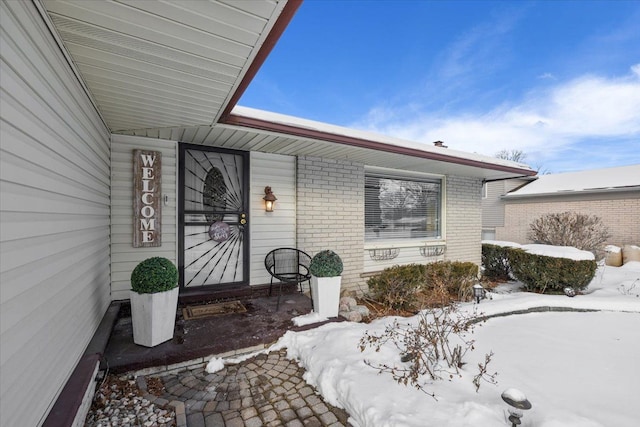 snow covered property entrance with brick siding