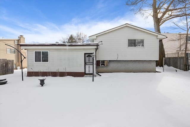 snow covered back of property featuring fence