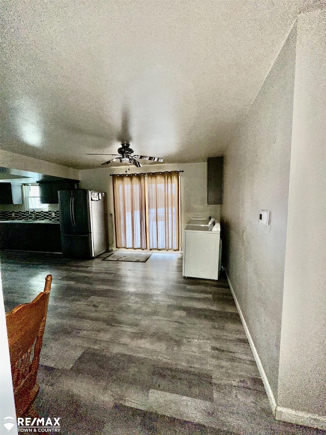 interior space featuring dark wood-style flooring, washer / clothes dryer, a ceiling fan, a textured ceiling, and baseboards