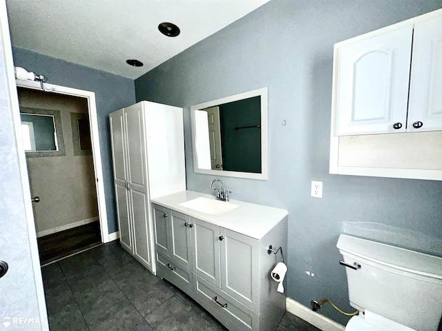 bathroom featuring tile patterned flooring, vanity, toilet, and baseboards