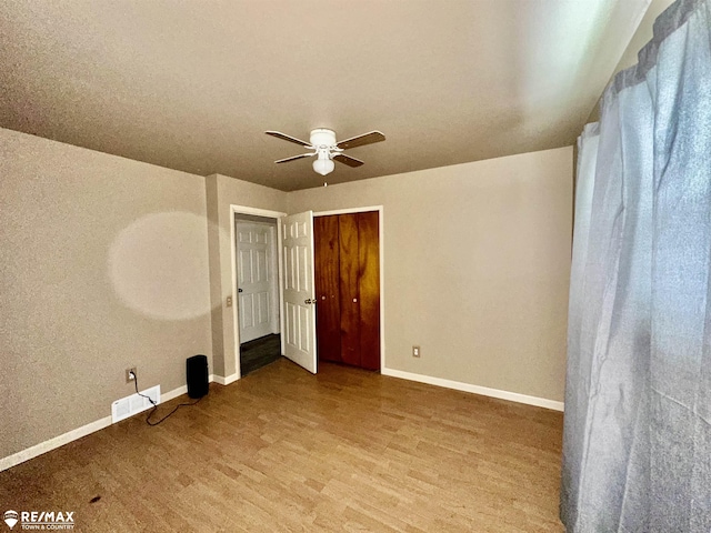 spare room featuring visible vents, baseboards, ceiling fan, and wood finished floors