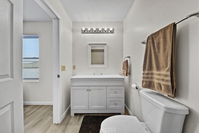 bathroom featuring toilet, wood finished floors, vanity, and baseboards