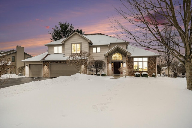 view of front facade with brick siding, an attached garage, and aphalt driveway