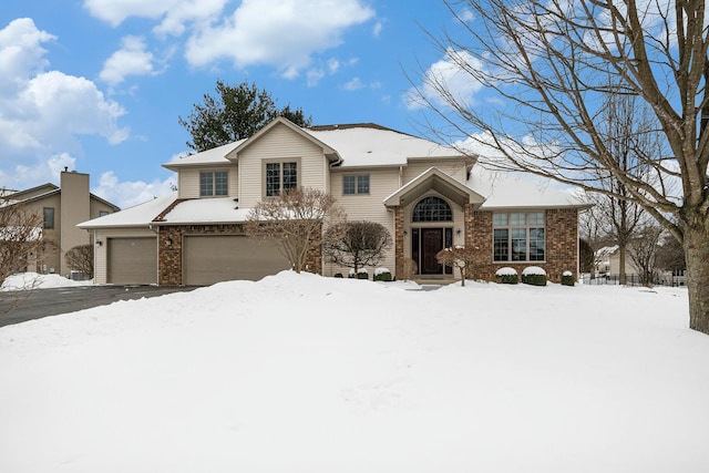 traditional-style home featuring aphalt driveway, brick siding, and a garage