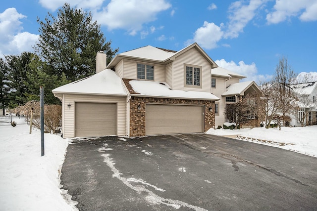 traditional home featuring aphalt driveway, brick siding, a chimney, and an attached garage