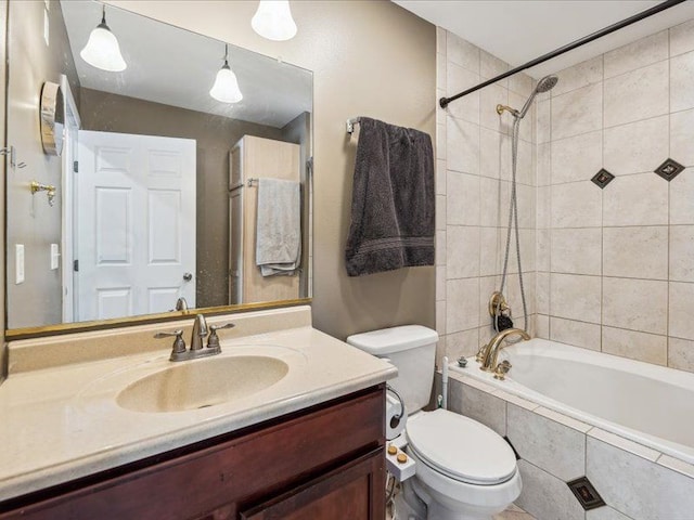 bathroom with toilet, tiled shower / bath combo, and vanity