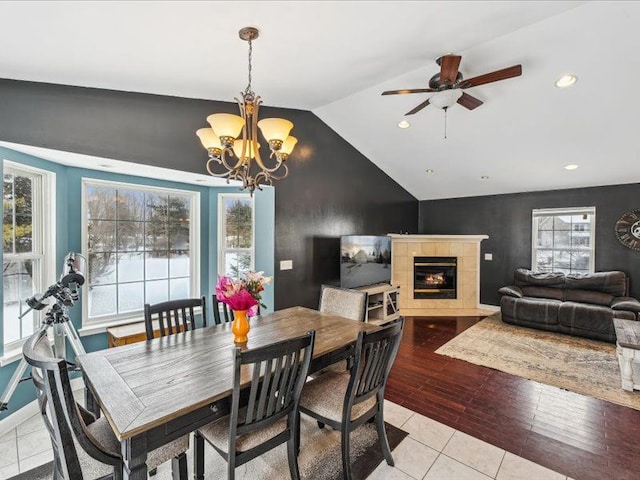 dining area with a healthy amount of sunlight, vaulted ceiling, a notable chandelier, and a fireplace