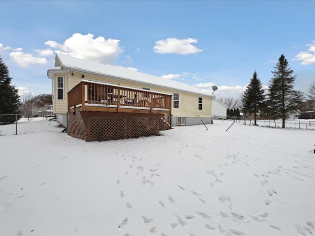 snow covered back of property with fence and a deck