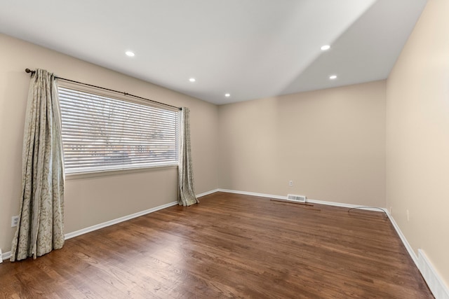 empty room featuring baseboards, dark wood-type flooring, visible vents, and recessed lighting