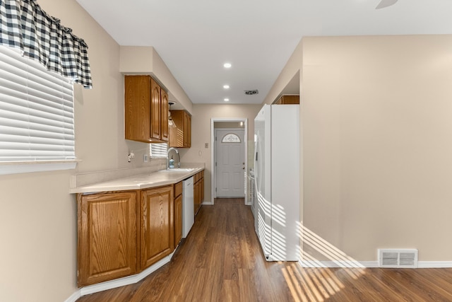 kitchen with light countertops, white appliances, brown cabinetry, and visible vents