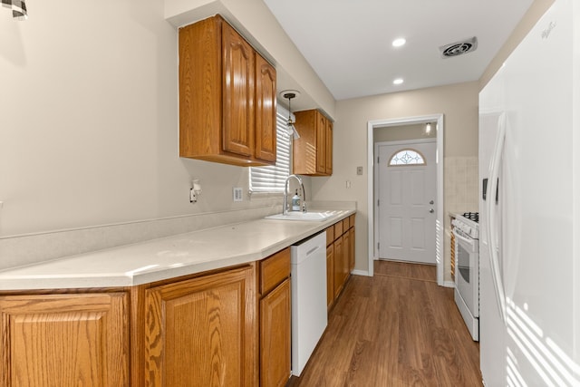 kitchen featuring brown cabinets, white appliances, light countertops, and a sink