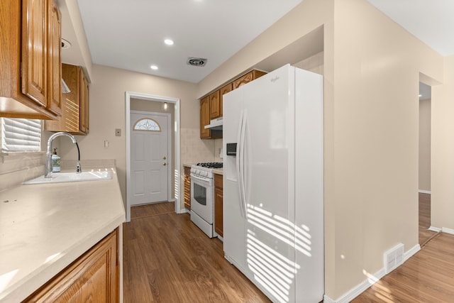 kitchen featuring white appliances, visible vents, light countertops, under cabinet range hood, and a sink