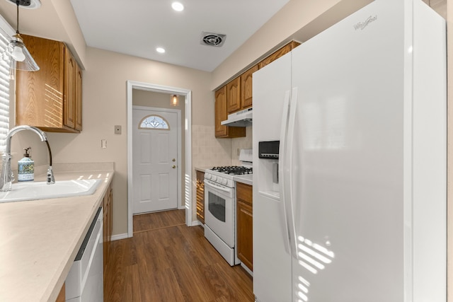 kitchen with white appliances, decorative light fixtures, light countertops, under cabinet range hood, and a sink