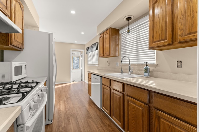 kitchen with white appliances, light countertops, a sink, and decorative light fixtures