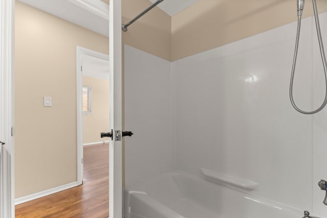 full bathroom with shower / bathing tub combination, wood finished floors, and baseboards