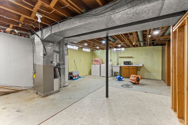 basement featuring heating unit, a sink, and independent washer and dryer