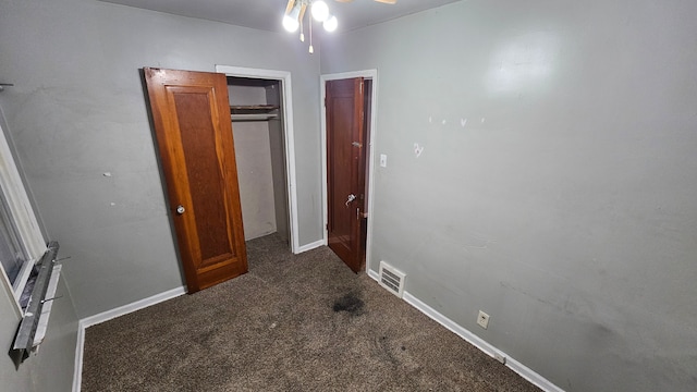 unfurnished bedroom with dark carpet, visible vents, and baseboards