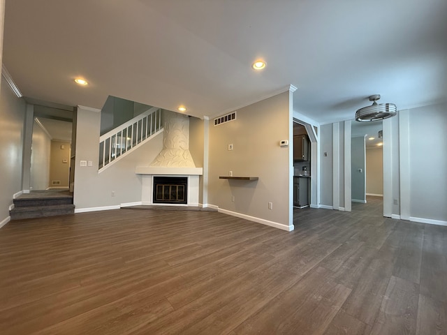 unfurnished living room featuring wood finished floors, visible vents, and baseboards