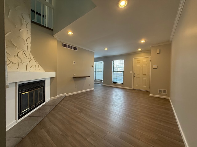 unfurnished living room with dark wood-style floors, a glass covered fireplace, visible vents, and baseboards